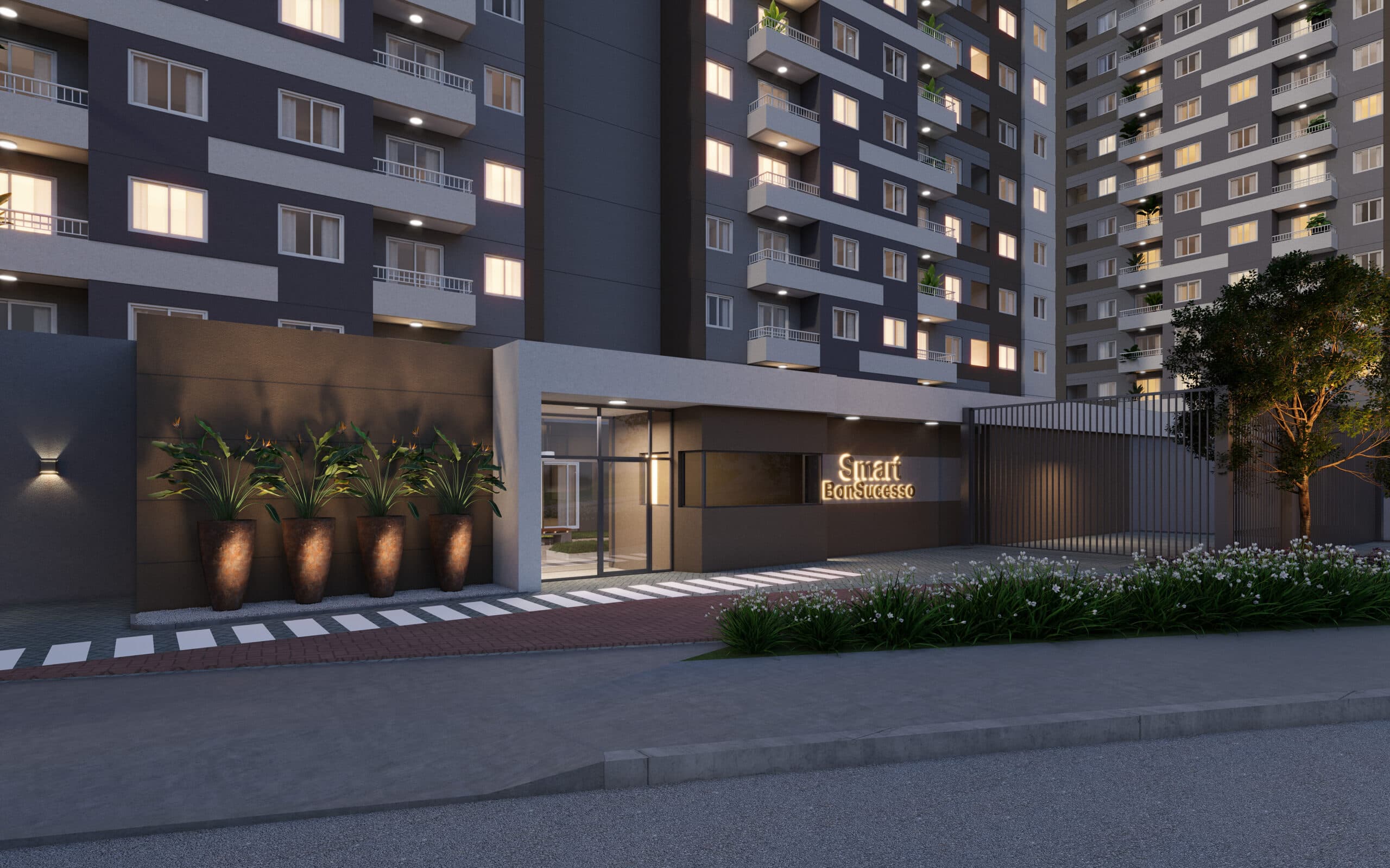 Fachada noturna de edifício residencial com entrada iluminada e paisagismo.